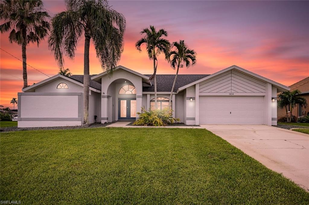 Ranch-style house featuring stucco siding, a front lawn, concrete driveway, an attached garage, and roof with shingles