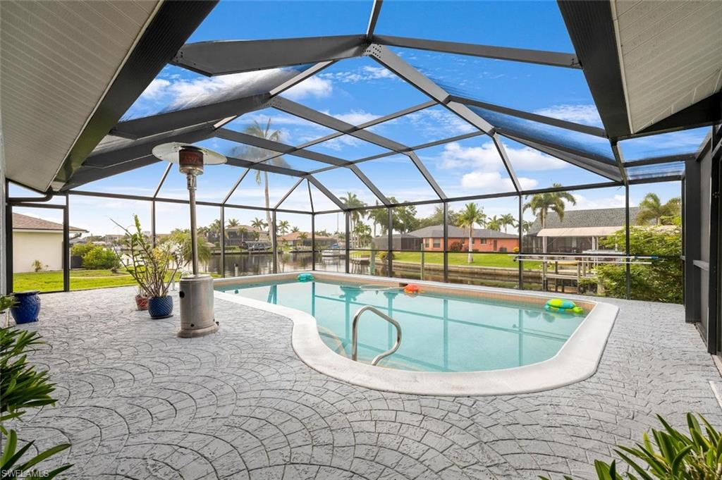 Outdoor pool with glass enclosure, a water view, a sunroom, a patio area, and a residential view