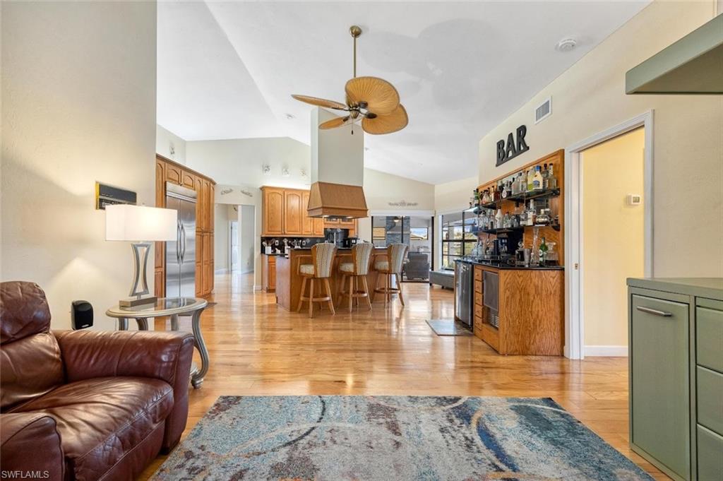 Living area featuring light wood finished floors, high vaulted ceiling, and ceiling fan