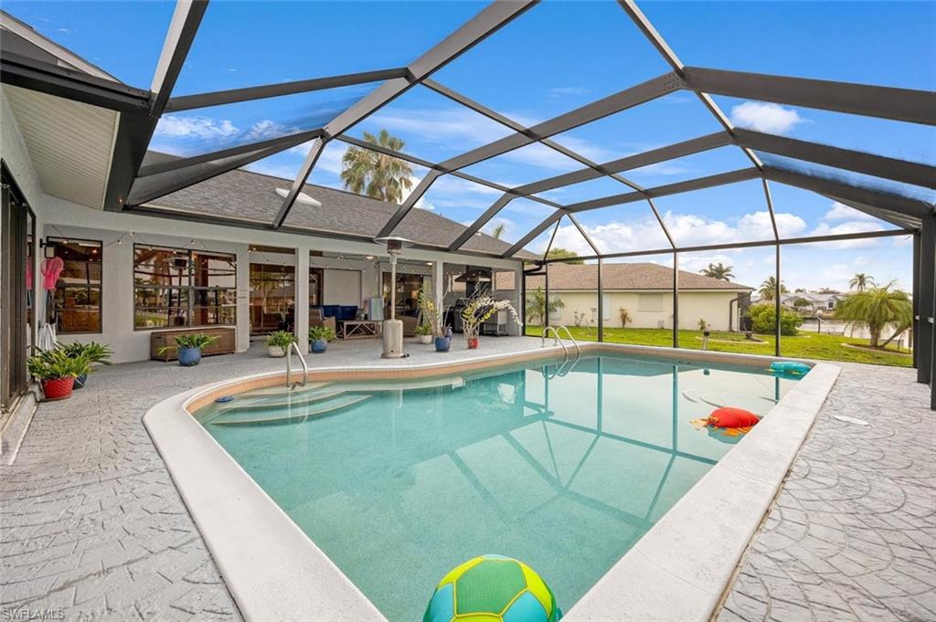 Swimming pool featuring a sunroom, glass enclosure, and a patio