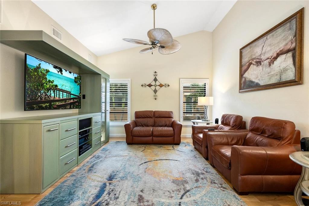 Living area featuring vaulted ceiling, plenty of natural light, a ceiling fan, and light wood-style floors
