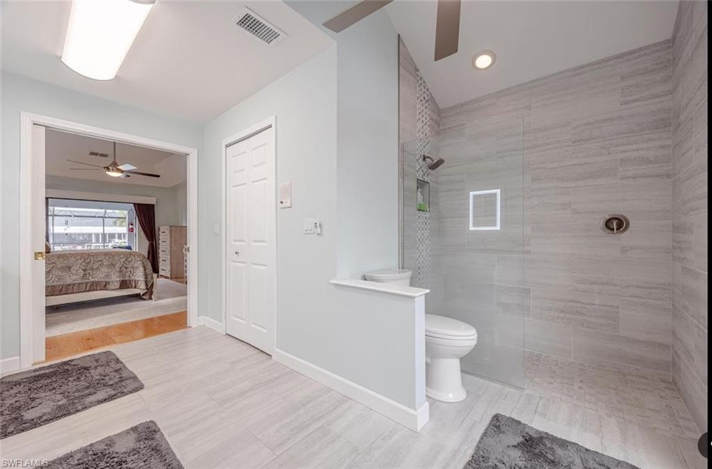Ensuite bathroom featuring ceiling fan, walk in shower, light wood-type flooring, and recessed lighting
