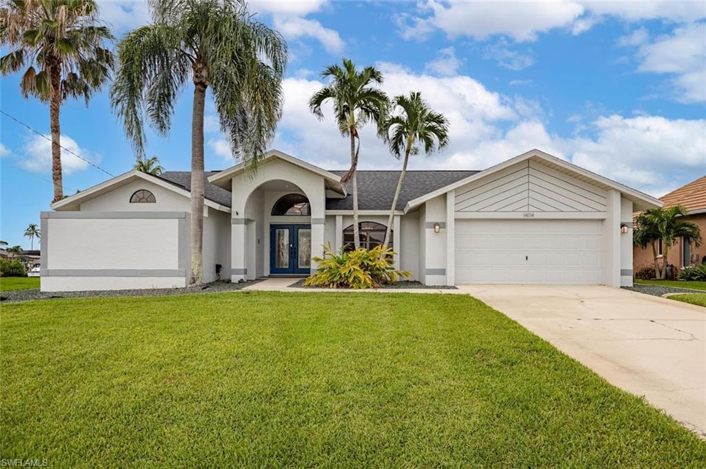 Single story home with stucco siding, a front lawn, french doors, and concrete driveway
