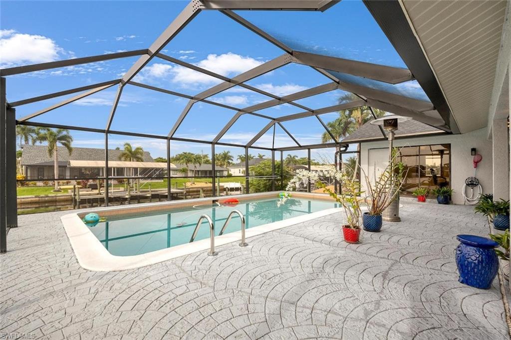 Swimming pool featuring glass enclosure, a sunroom, and a patio area