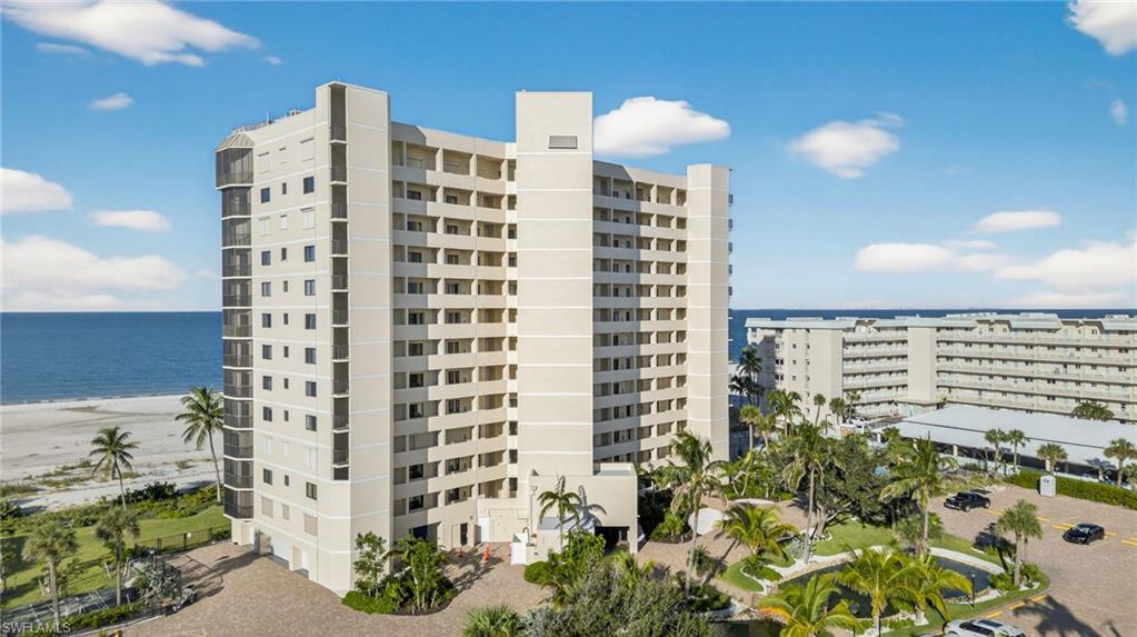 View of apartment building / complex featuring view of water and beach