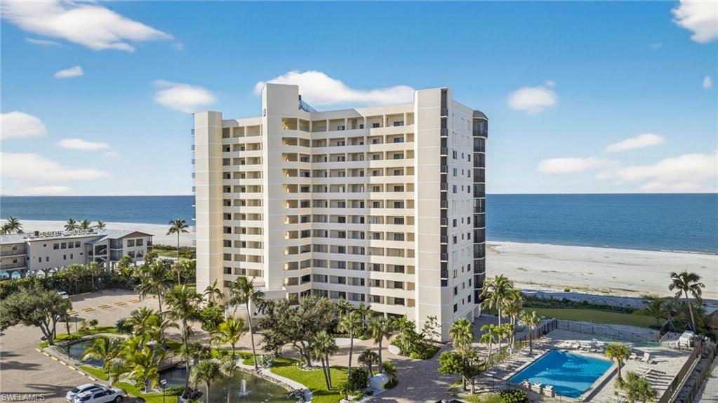 View of apartment building / complex featuring view of water and beach and a community pool