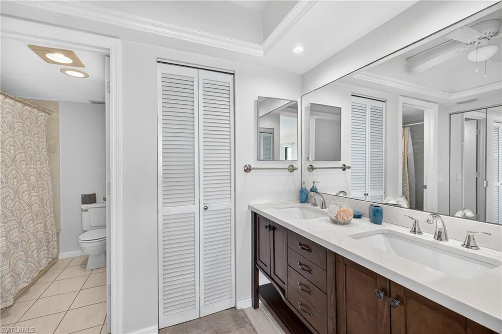 Bathroom featuring a closet, double vanity, light tile patterned flooring, recessed lighting, and ornamental molding