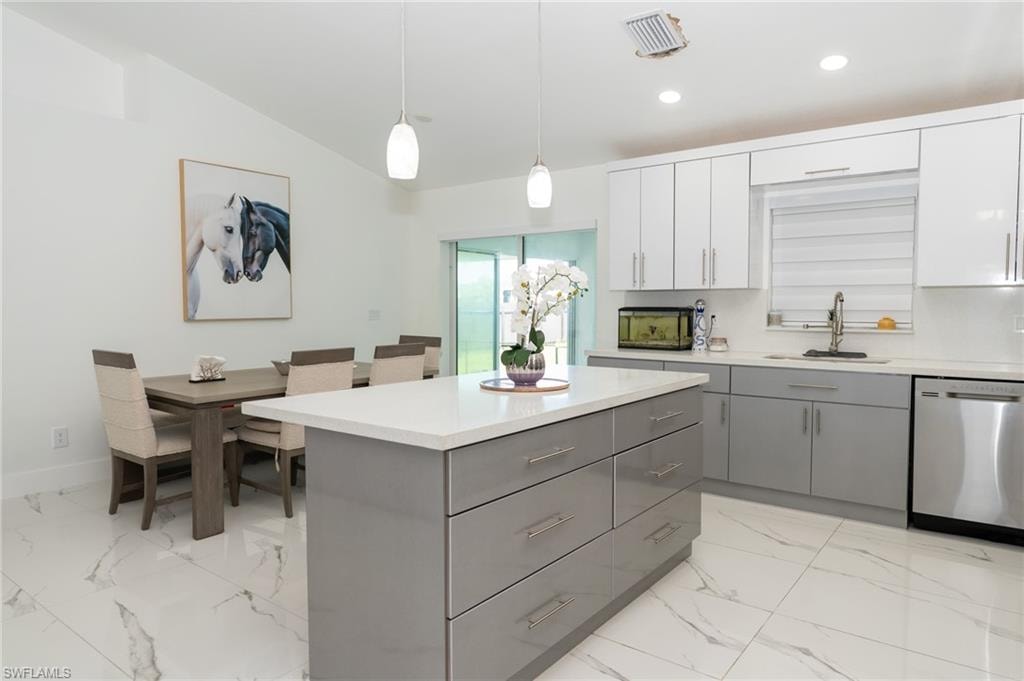 Kitchen with gray cabinetry, dishwasher, a center island, pendant lighting, and light marble finish flooring