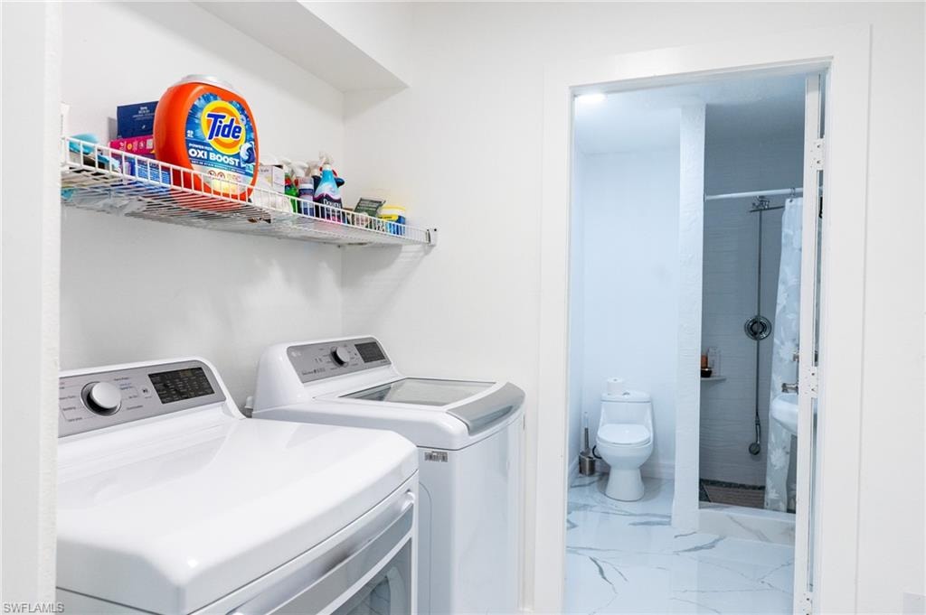 Laundry area featuring light marble finish floors and washing machine and clothes dryer