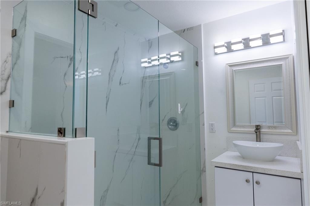 Full bathroom featuring vanity and a marble finish shower