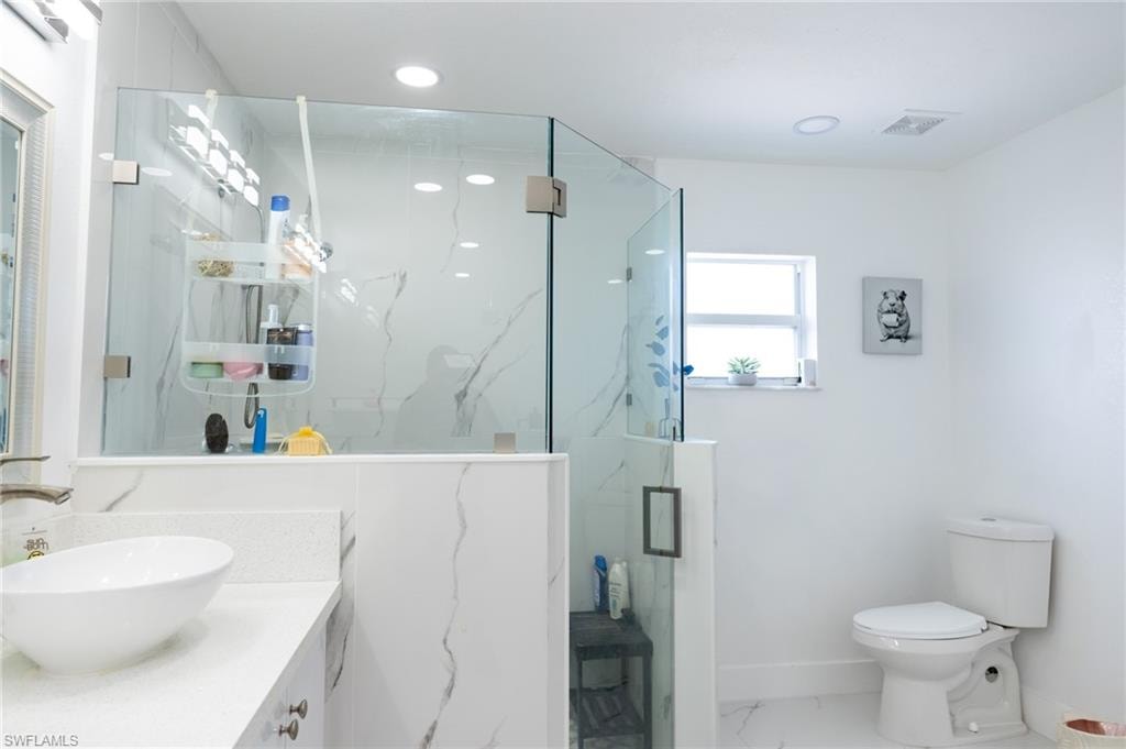 Full bathroom with marble finish floors, a marble finish shower, vanity, and recessed lighting