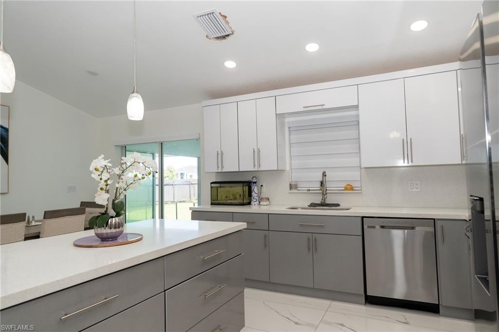 Kitchen featuring gray cabinets, hanging light fixtures, appliances with stainless steel finishes, white cabinets, and recessed lighting