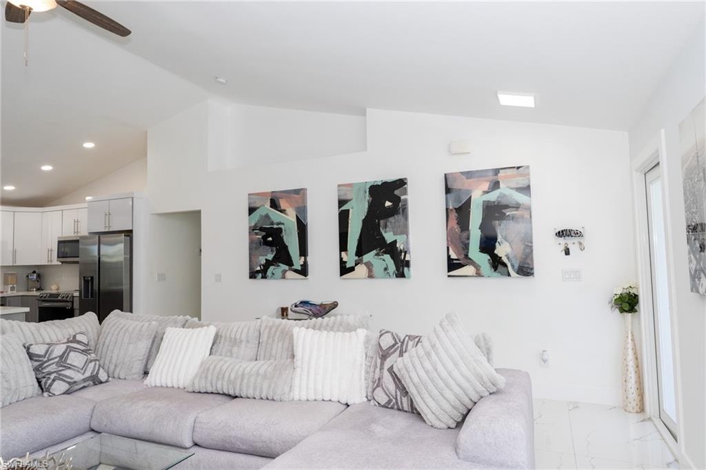 Living area featuring lofted ceiling, light marble finish floors, recessed lighting, and ceiling fan