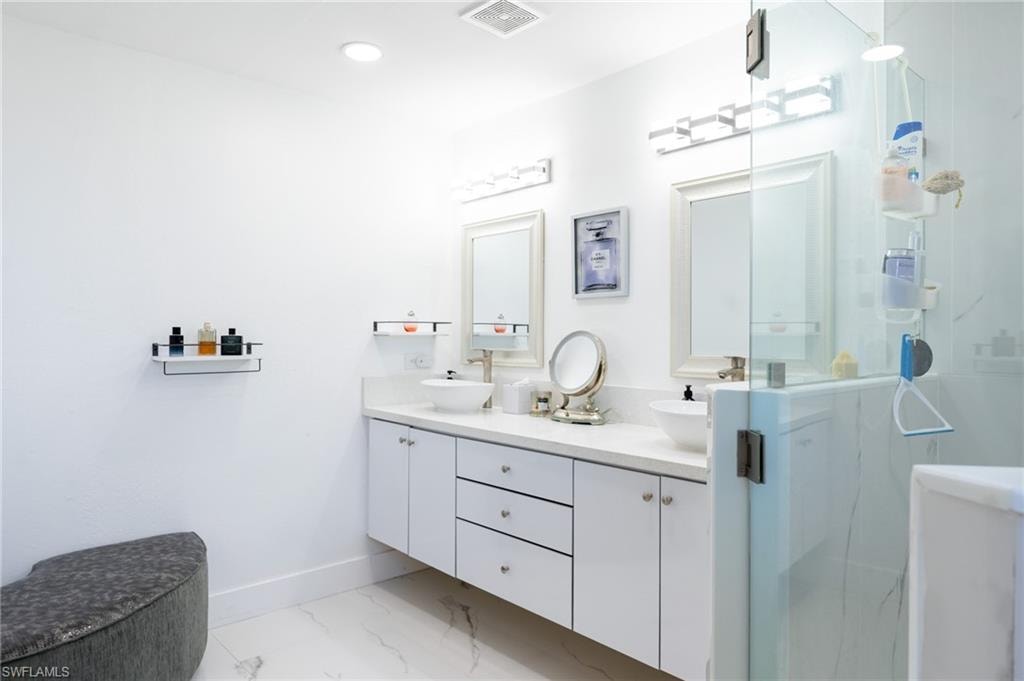 Full bathroom with double vanity, a marble finish shower, light marble finish flooring, and recessed lighting