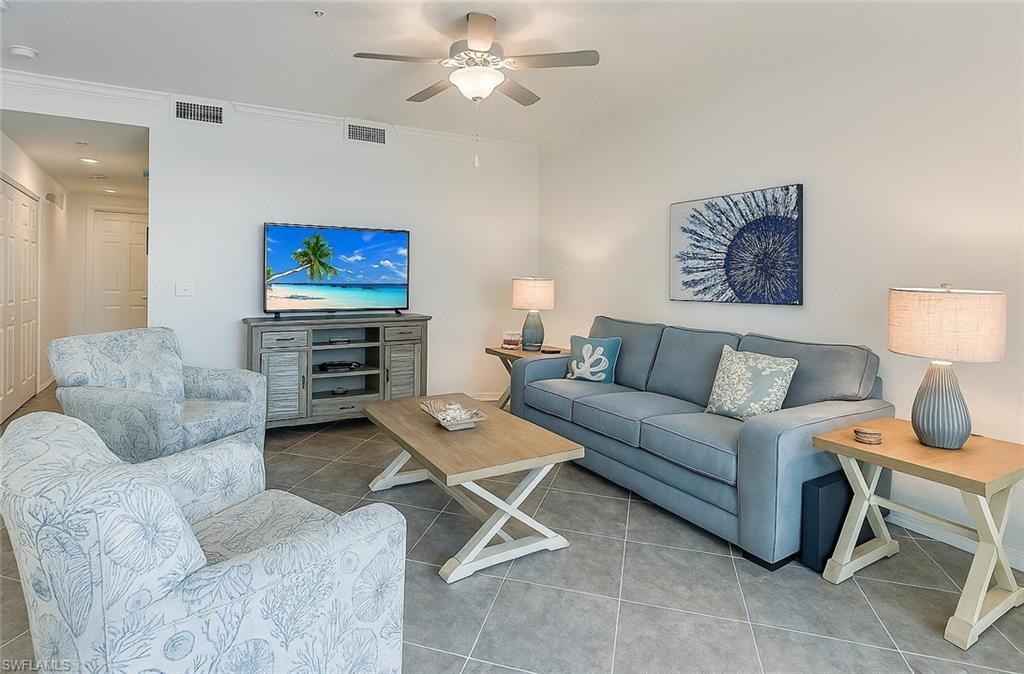 Tiled living room with ceiling fan and crown molding