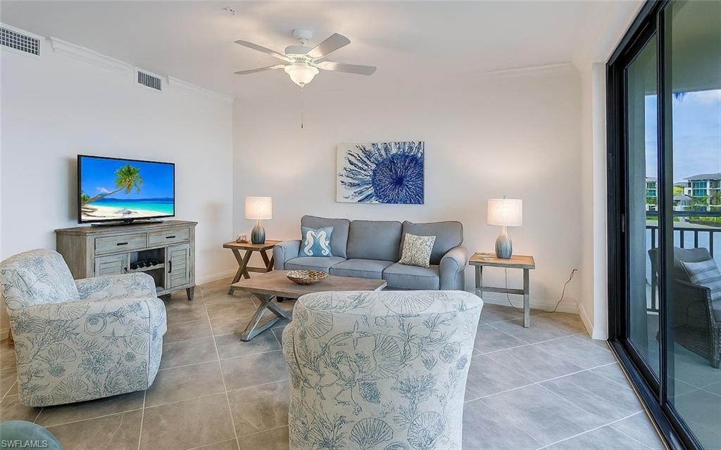 Tiled living area featuring ornamental molding and ceiling fan