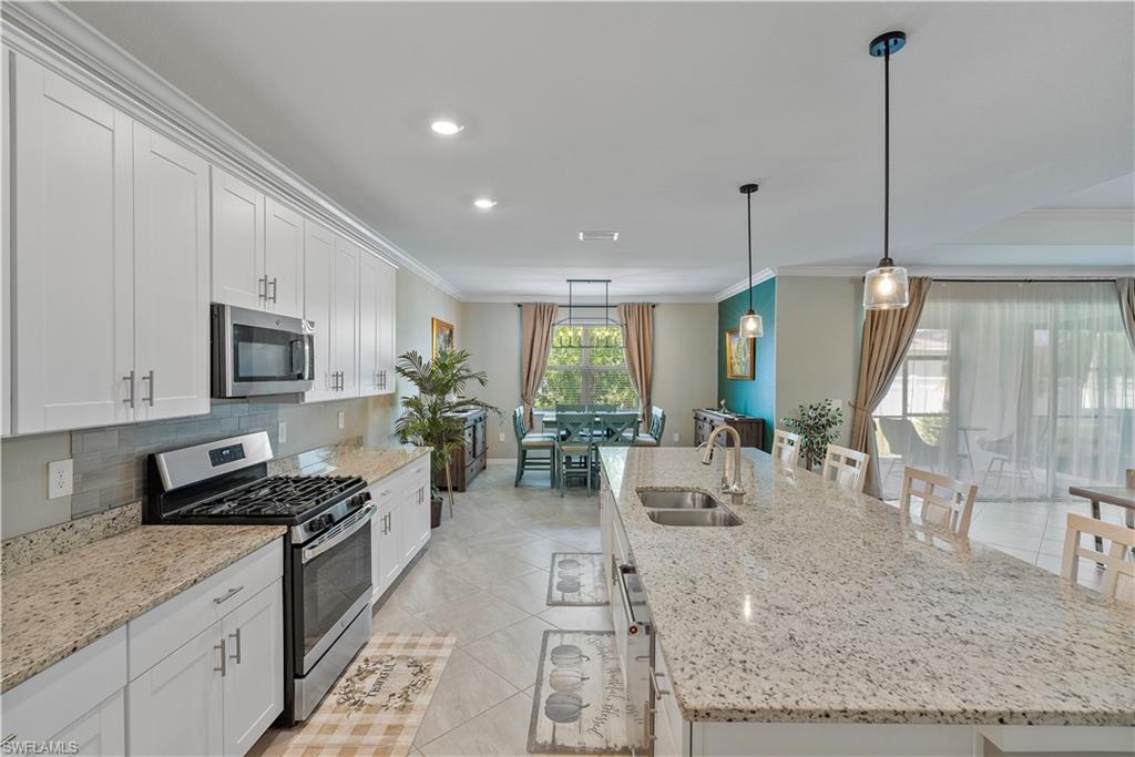 Kitchen featuring ornamental molding, a large island, stainless steel appliances, and sink