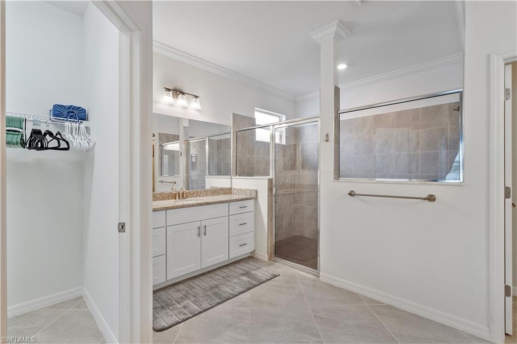 Bathroom with crown molding, vanity, tile patterned floors, and a shower with shower door