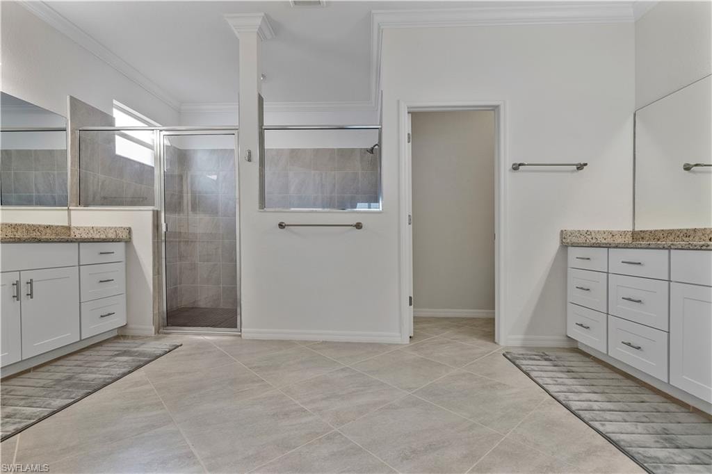 Bathroom featuring ornamental molding, a shower with shower door, and vanity