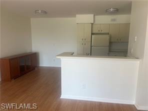Kitchen featuring light countertops, black appliances, exhaust hood, a peninsula, and dark wood-style floors