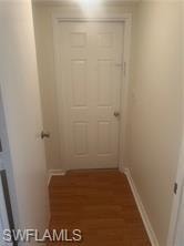 Hall featuring dark wood-style flooring and baseboards