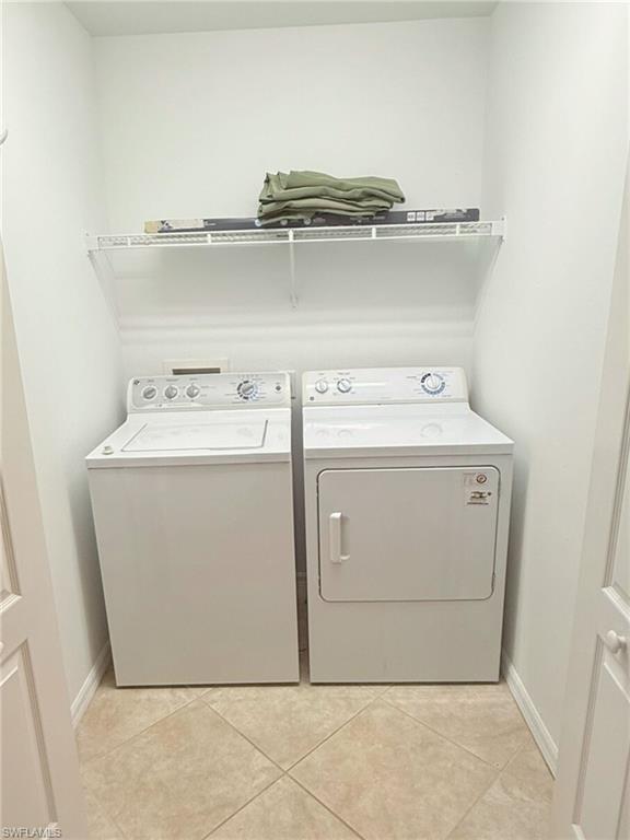 Laundry room with light tile patterned floors and washing machine and clothes dryer
