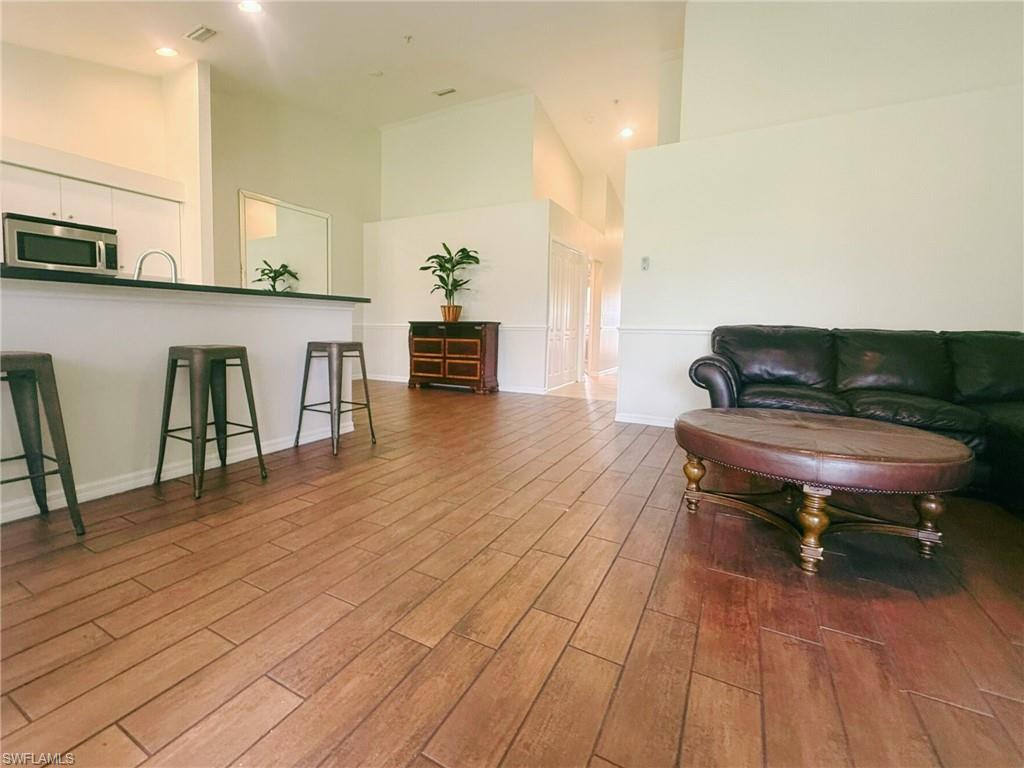 Living area with a high ceiling, dark wood-type flooring, and recessed lighting