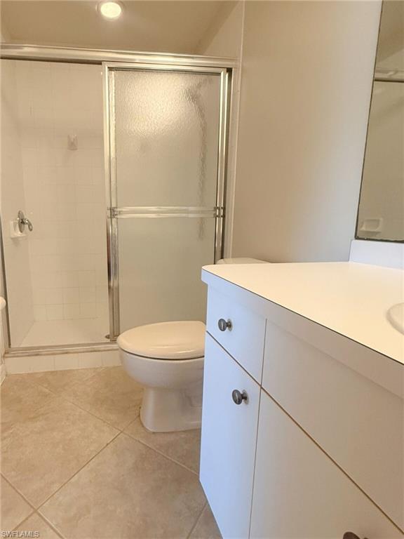 Bathroom featuring vanity, light tile patterned floors, and a shower stall