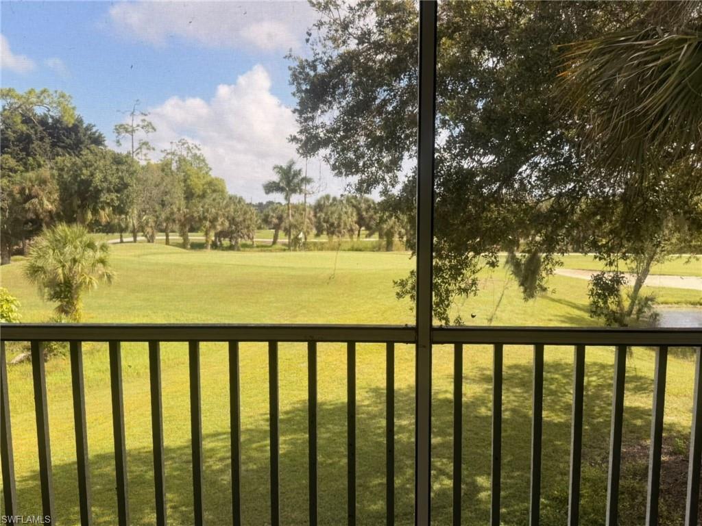 View of green lawn featuring view of wooded area and a sunroom