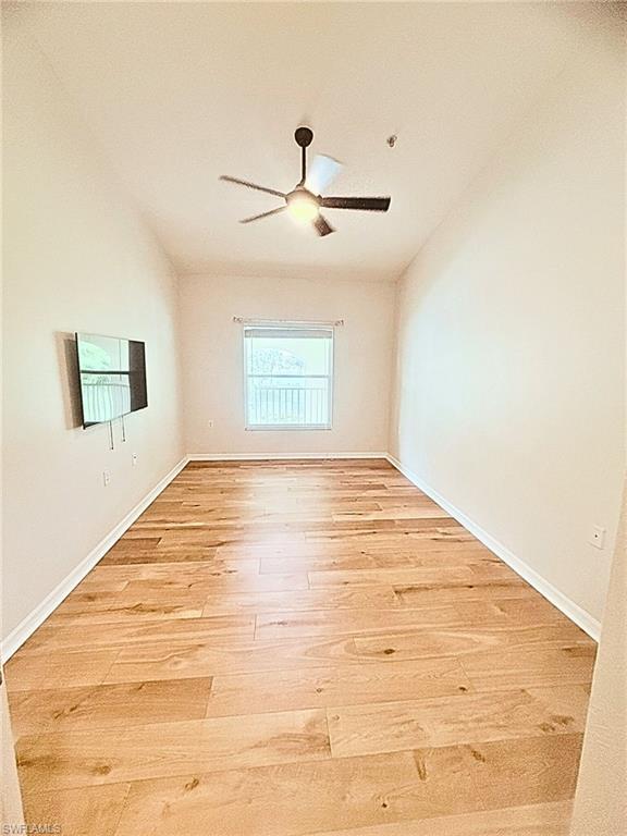 Spare room with vaulted ceiling, light wood-style flooring, and a ceiling fan