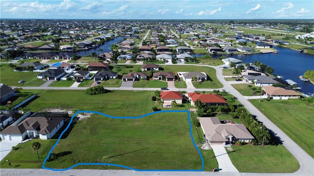Aerial perspective of suburban area with property parcel outlined and a large body of water