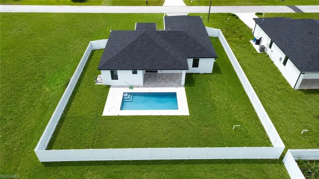 Private backyard featuring a swimming pool with surrounding patio, green lawn, and full perimeter fencing