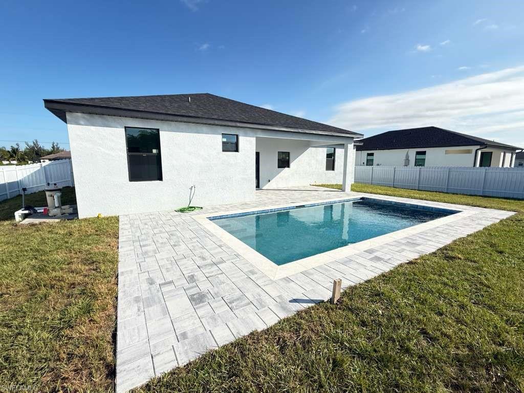 Back of house featuring a fenced backyard, a patio area, stucco siding, and a shingled roof