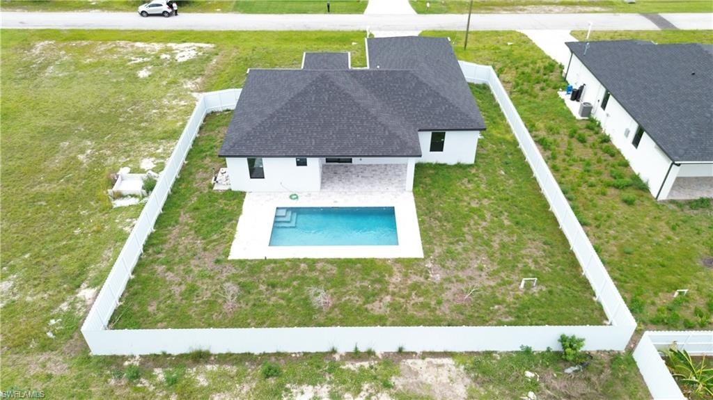 Contemporary white stucco exterior featuring a dark shingle roof, a private swimming pool, and a spacious surrounding patio