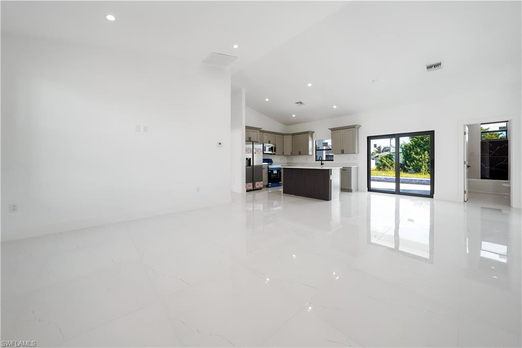 Unfurnished living room featuring lofted ceiling and recessed lighting