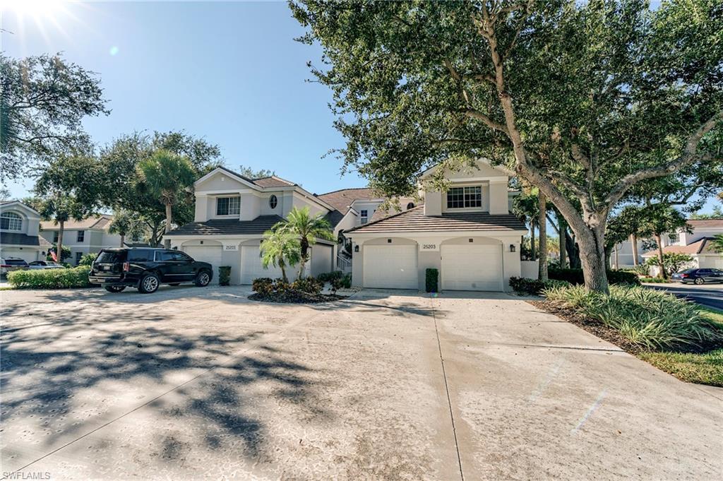 Coach Home featuring driveway, stucco siding, an attached garage, and a tiled roof