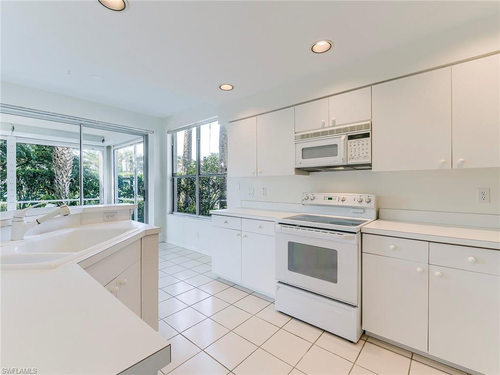 Kitchen with white appliances, light countertops, white cabinets, and recessed lighting
