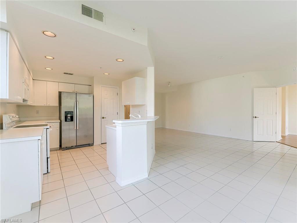Kitchen featuring white appliances, white cabinetry, light countertops, light tile patterned floors, and recessed lighting