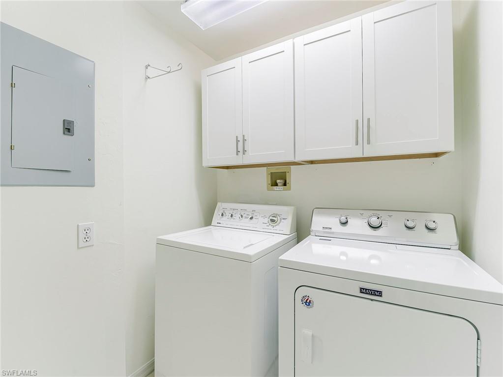 Laundry room with electric panel, washer and clothes dryer, and cabinet space