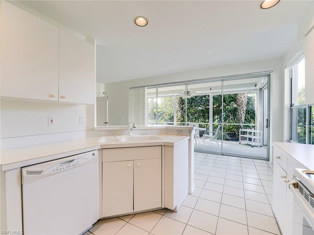 Kitchen with white appliances, white cabinetry, a peninsula, light countertops, and light tile patterned flooring