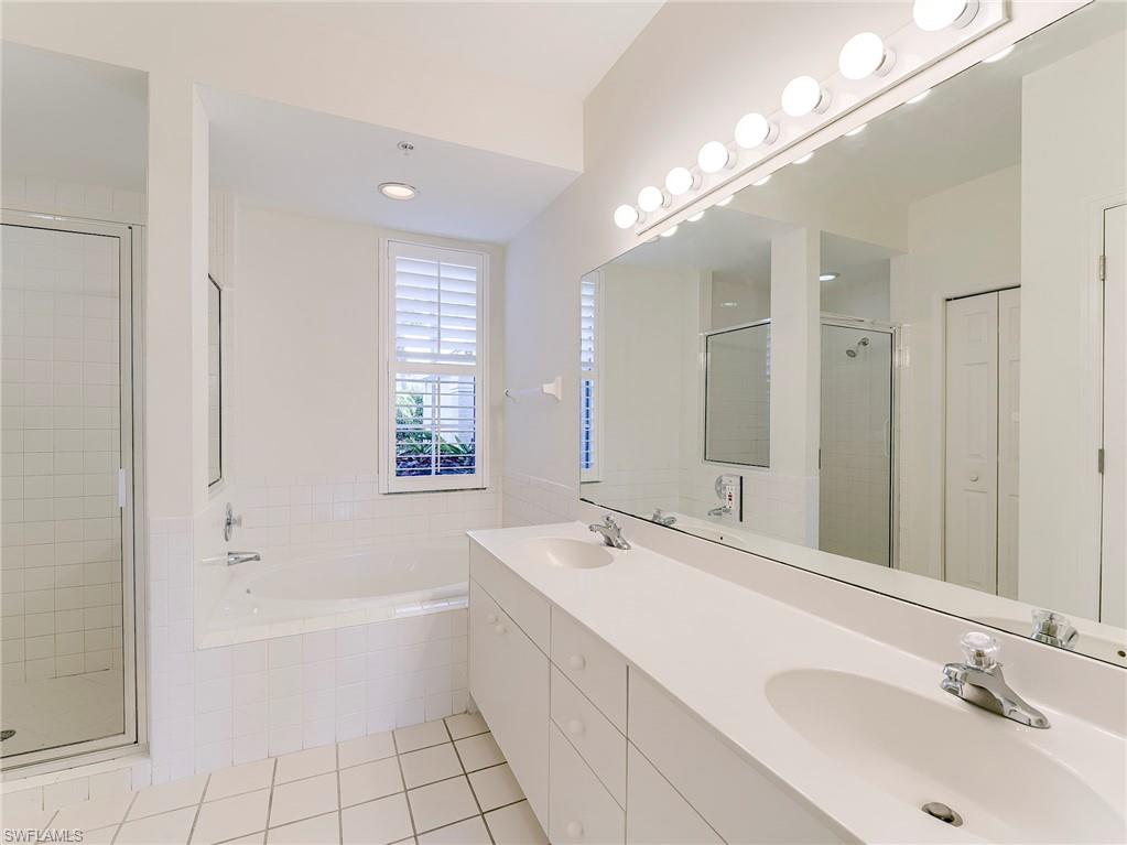 Bathroom featuring a closet, light tile patterned flooring, a garden tub, and a shower stall