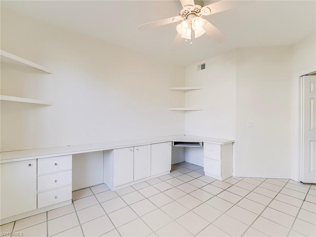 Unfurnished office featuring built in study area, ceiling fan, and light tile patterned floors