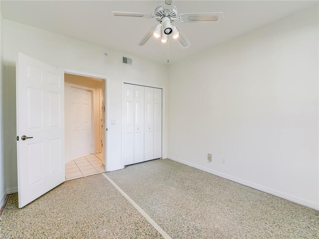 Unfurnished bedroom with a closet, ceiling fan, and speckle patterned floor
