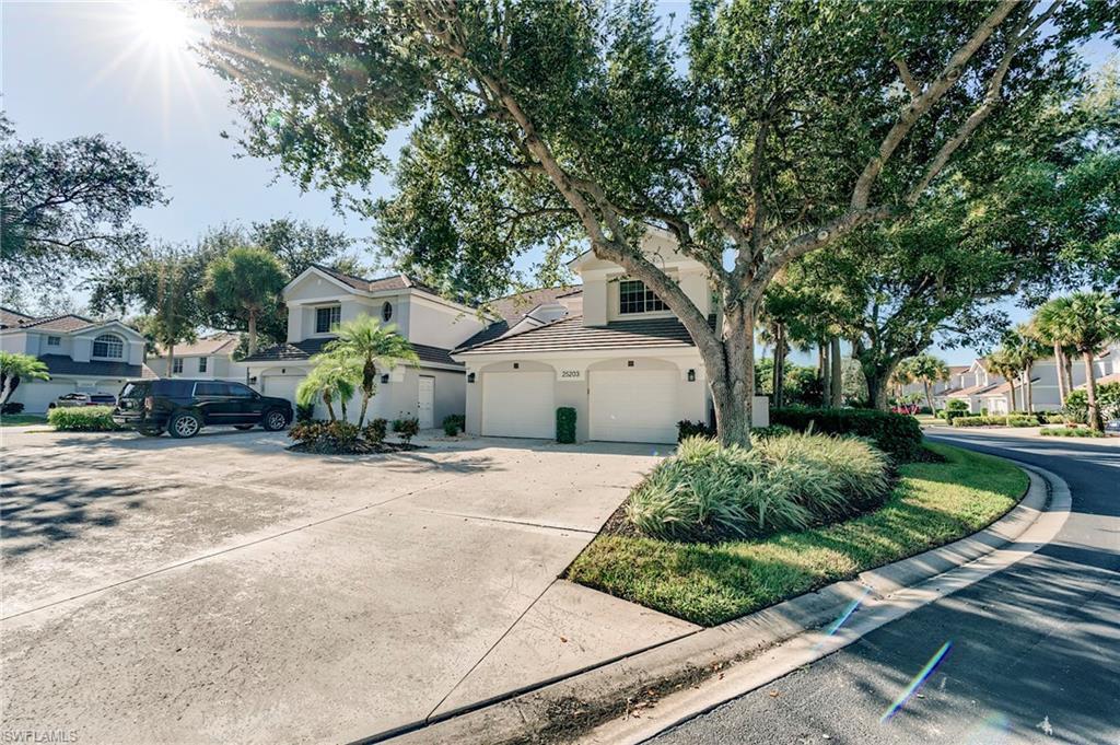 View of front facade featuring a garage, concrete driveway, stucco siding, and a residential view