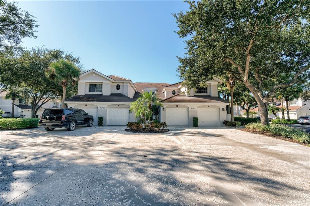 Coach Home with driveway, an attached garage, a tiled roof, and stucco siding