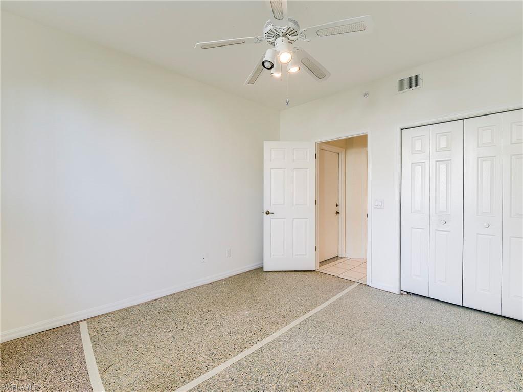 Unfurnished bedroom with speckle patterned floor, a closet, and a ceiling fan