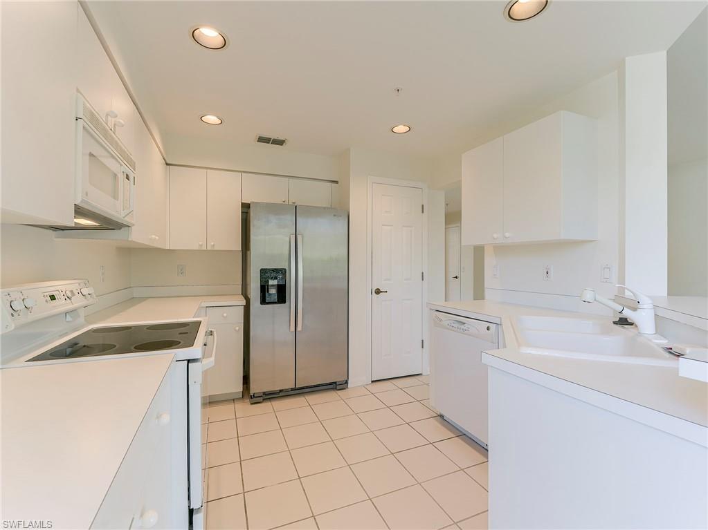 Kitchen with white appliances, light countertops, recessed lighting, white cabinets, and light tile patterned flooring