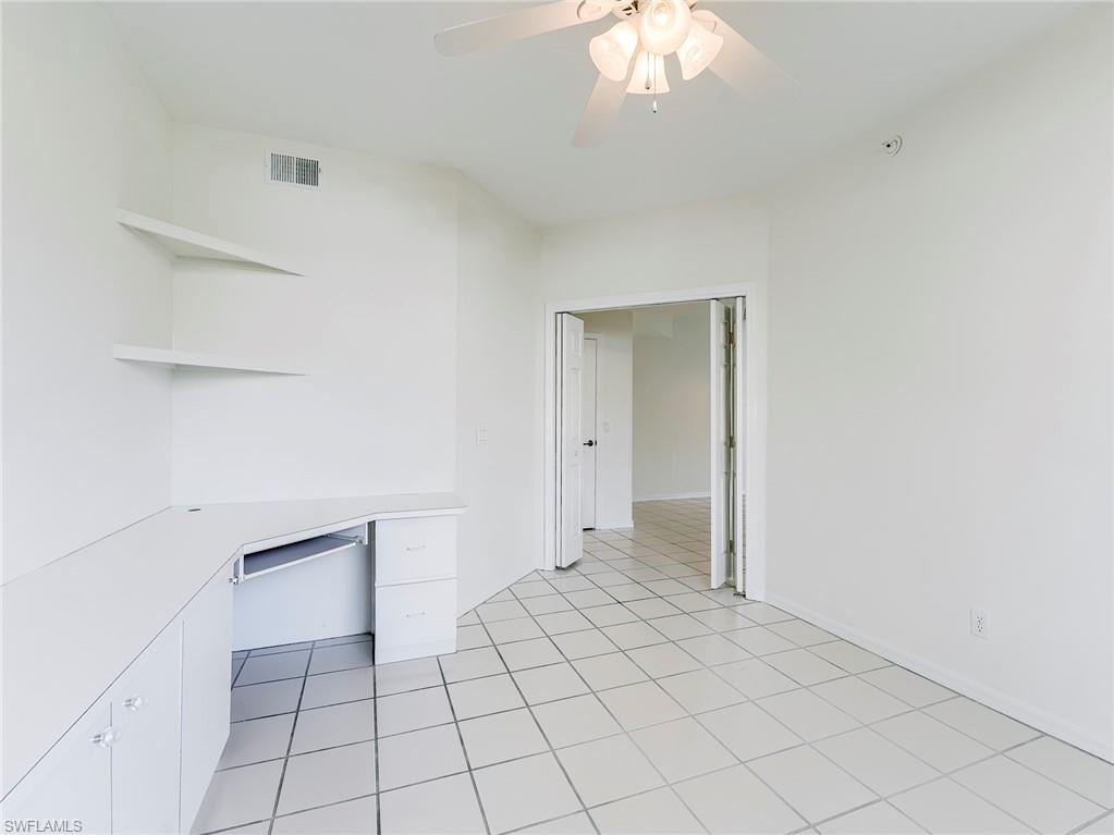 Unfurnished office featuring a ceiling fan, built in desk, and light tile patterned floors