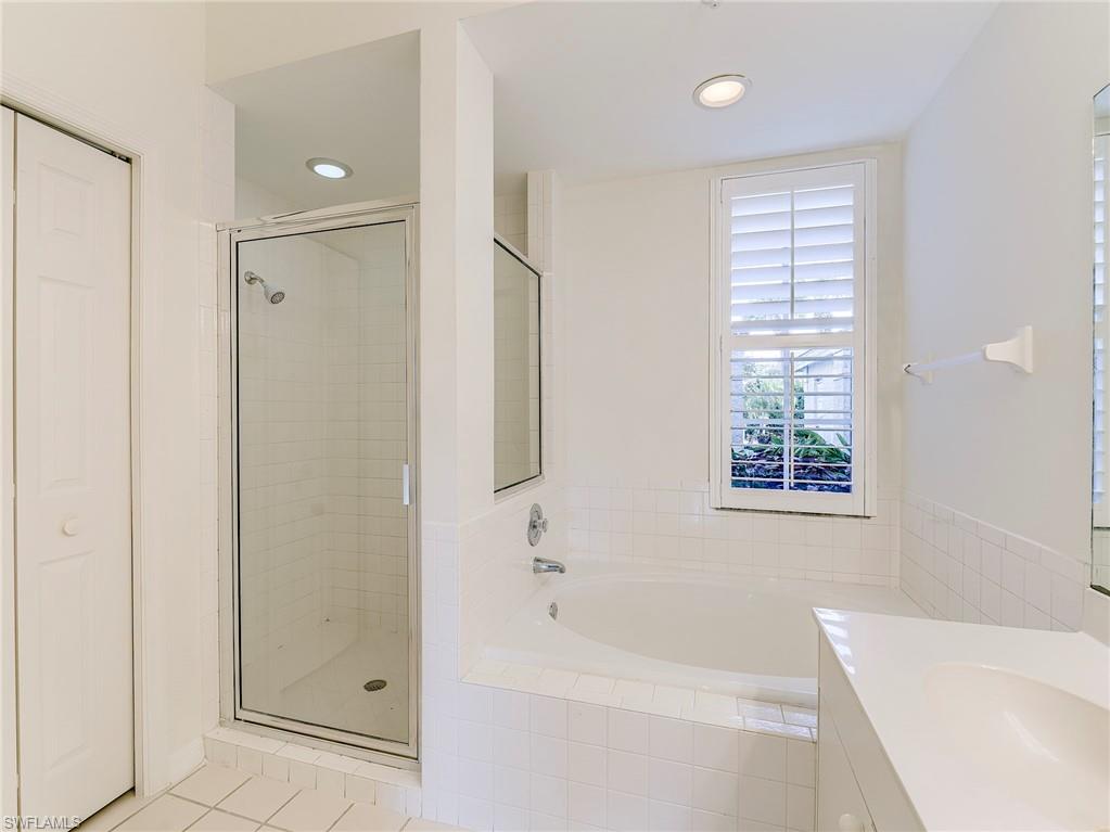 Bathroom with a bath, a stall shower, vanity, light tile patterned floors, and recessed lighting