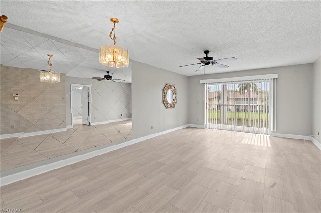 Unfurnished living room with a chandelier, a ceiling fan, a textured ceiling, and light wood-style flooring